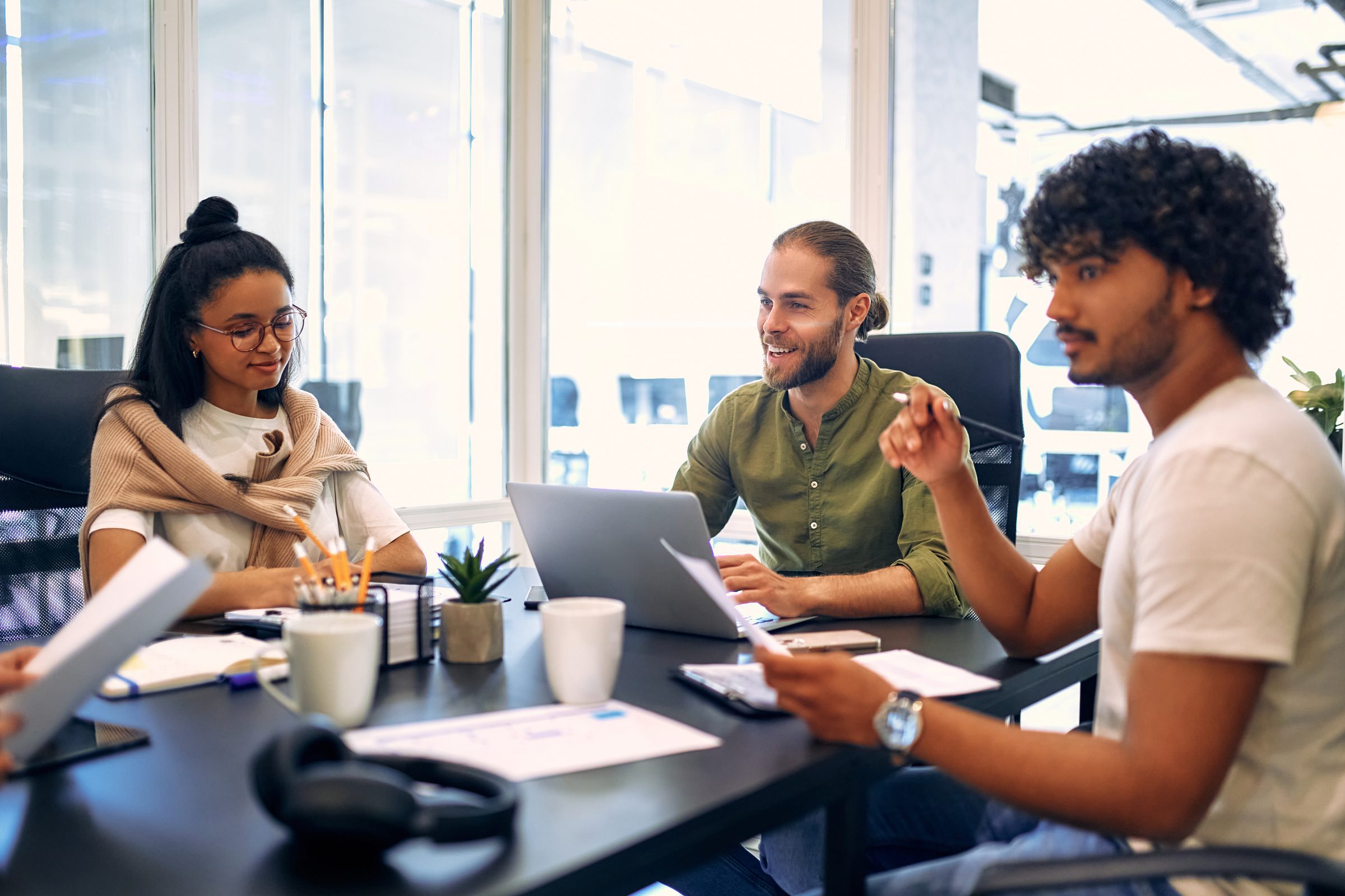 Three people working together at a table with laptops