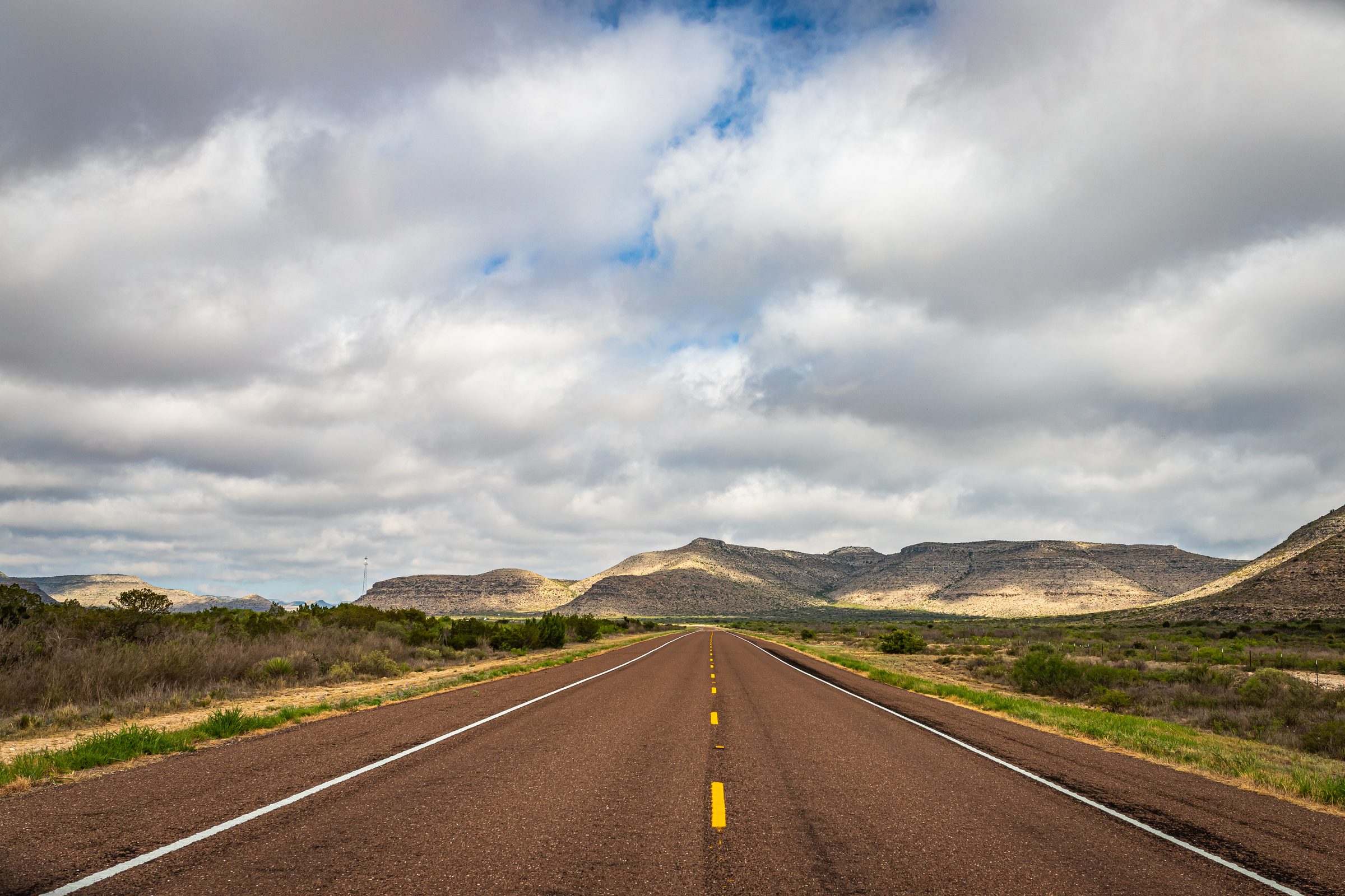An open highway across Texas, hills on the horizon